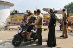 Policemen check a scooter at a security barricade on the road leading to a disputed religious site where Hindu religious groups are demanding the construction of a temple in Ayodhya, India, Oct. 22, 2019.