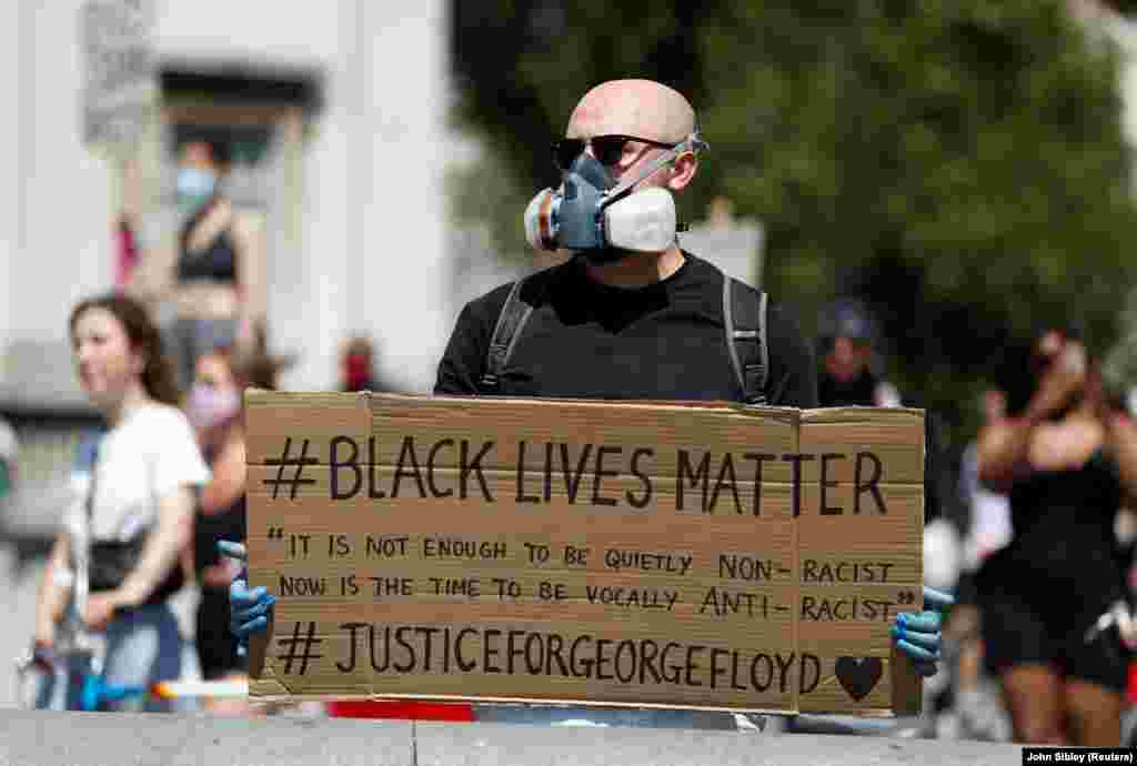 Great Britain, London, A person wearing a protective face mask holds up a Black Live Matters sign during a protest against the death in Minneapolis police custody of African-American man George Floyd Nchini Uingereza mtu akiwa amevaa barakoa amebeba bango linalosema &quot;Maisha ya Watu Weusi Muhimu&quot; wakati wa maandamano dhidi ya vitendo vya polisi wa Minneapolis takati walipomkamata George Floyd.