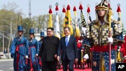 Pemimpin Korea Utara Kim Jong Un, kiri, and Presiden Korea Selatan Moon Jae-in berjalan bersama di desa perbatasan Panmunjom di Zona Demiliterisasi, 27 April 2018. 