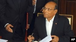 FILE - Tunisian President Moncef Marzouki reacts as he signs the new Constitution in Tunis, Jan. 27, 2014