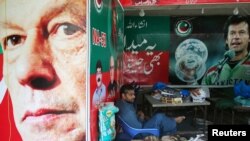 A vendor sits next to images of cricket star-turned-politician Imran Khan, chairman of Pakistan Tehreek-e-Insaf (PTI), at a market in Islamabad, Pakistan, July 27, 2018. Khan, who declared victory in this week's election, has called for better ties with India.