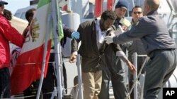 A man is helped out of an Italian Coastguard boat upon his arrival in Lampedusa, southern Italy, April 6, 2011