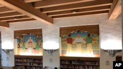 FILE - Students study below a series of murals in the west wing of the University of New Mexico's historic Zimmerman Library in Albuquerque, N.M., Oct. 8, 2018. 