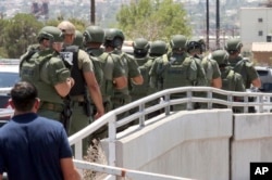 Law enforcement officers make their way along a walkway to the scene of a shooting at a shopping mall in El Paso, Texas, Aug. 3, 2019.
