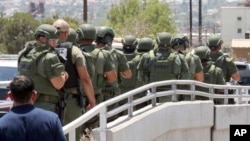 Law enforcement officers make their way along a walkway to the scene of a shooting at a shopping mall in El Paso, Texas, on Saturday, Aug. 3, 2019. 