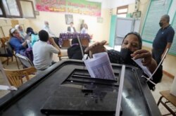 Seorang perempuan memasukkan surat suaranya ke dalam kotak suara di sebuah TPS di Kairo, Mesir, 11 Agustus 2020. (REUTERS/Mohamed Abd El Ghany)