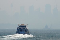 A ferry makes its way from Taronga Zoo to Circular Quay, with the Sydney skyline barely visible in the background through smoke haze from bushfires, in Sydney Harbor, Australia, Dec. 5, 2019.