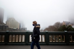 FILE - A person in a protective face mask walks along the Princes Bridge amidst a lockdown in response to an outbreak of the coronavirus disease (COVID-19) in Melbourne, Australia, July 17, 2020. (AAP Image/Daniel Pockett via Reuters)