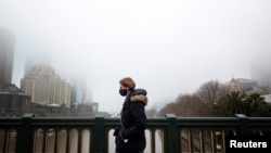 A person in a protective face mask walks along the Princes Bridge amidst a lockdown in response to an outbreak of the coronavirus disease (COVID-19) in Melbourne, Australia, July 17, 2020. (AAP Image/Daniel Pockett via Reuters)