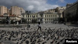 A man wearing a protective face mask makes his way on the empty Kotzia square during the COVID-19 outbreak, in Athens, Greece, on April 7, 2020. 