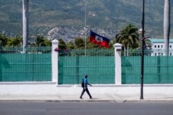 Un hombre pasa frente al Palacio Presidencial de Haití donde ondea a media asta la bandera haitiana, en Puerto Príncipe, el 10 de julio de 2021.