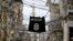 FILE - An Islamic State flag hangs amid electric wires over a street in southern Lebanon, Jan. 19, 2016.
