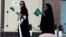 FILE - Saudi women hold national flags as they walk on a street during Saudi National Day in Riyadh, Saudi Arabia.
