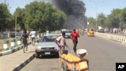 Mutane suna gudu yayin da hayaki ke shiga cikin samaniya bayan da bom ya fashe a inda sojoji ke girke a garin Maiduguri, Janairu 14, 2014.