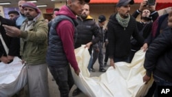 Palestinians carry white sacks containing the bodies of those killed in overnight Israeli airstrikes on the Maghazi refugee camp at Al-Aqsa Hospital in Deir al-Balah, central Gaza Strip, Dec. 28, 2024.