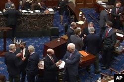 FILE - In this image from video, Republican senators and staff talk on the floor at the second impeachment trial of former President Donald Trump in the Senate, at the U.S. Capitol in Washington, Feb. 13, 2021. (Senate Television via AP)