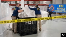 In this image provided by the FBI, FBI special agents assigned to the evidence response team process material recovered from the high altitude balloon recovered off the coast of South Carolina, Thursday, Feb. 9, 2023, at the FBI laboratory in Quantico, Va., (FBI via AP)