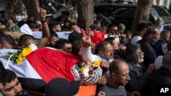 FILE - Mourners carry the bodies of two men killed in clashes with settlers during their funeral in the West Bank city of Ramallah, October 19, 2023. 