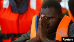 FILE: An African rescued by the Migrant Offshore Aid Station reacts as the ship Phoenix reaches Sicily's port of Pozzallo. The charity provided this courtesy photo Oct. 5, 2014. 