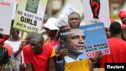 Orang-orang membawa poster menuntut dikembalikannya para siswi yang diculik militan Boko Haram di desa Chibok, Lagos (9/5/2014). 