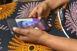 FILE - Anifa holds her phone, displaying a photo of former World Health Organization doctor Boubacar Diallo, of Canada, during an interview in the eastern Congo town of Goma, March 5, 2021.
