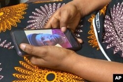 FILE - Anifa holds her phone, displaying a photo of former World Health Organization doctor Boubacar Diallo, of Canada, during an interview in the eastern Congo town of Goma, March 5, 2021.