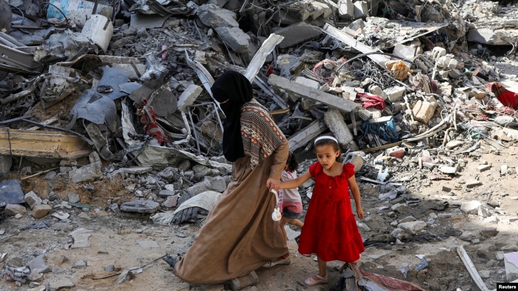 Una mujer y una niña caminan entre los escombros, después de los ataques israelíes en el área donde los rehenes israelíes fueron rescatados el sábado, en el campo de refugiados de Nuseirat en el centro de la Franja de Gaza, el 9 de junio de 2024.