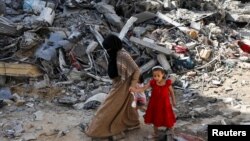 Una mujer y una niña caminan entre los escombros, después de los ataques israelíes en el área donde los rehenes israelíes fueron rescatados el sábado, en el campo de refugiados de Nuseirat en el centro de la Franja de Gaza, el 9 de junio de 2024. 