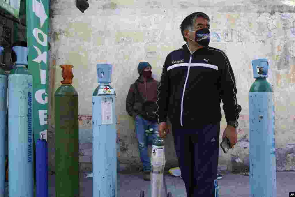 Jorge Perez lines up to refill an oxygen tank for a family member sick with COVID-19 in Mexico City, Dec. 27, 2020.