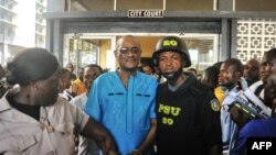 Former deputy governor of the Central Bank of Liberia Charles Sirleaf (C), the son of LIberia's former president Ellen Johnson Sirleaf, is escorted outside the City Court of Monrovia on March 4, 2019, where he appeared in court and charged with economic sabotage.