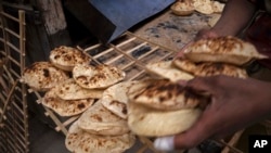A worker collects Egyptian traditional 'baladi' flatbread, at a bakery, in el-Sharabia, Shubra district, Cairo, Egypt, Wednesday, March 2, 2022.