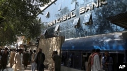 Afghans wait for hours to try to withdraw money, in front a bank, in Kabul, Aug. 15, 2021.