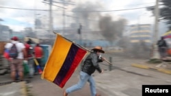 A demonstrator runs while holding an Ecuadorian flag during a protest against Ecuador's President Lenin Moreno's austerity measures in Quito, Ecuador, Oct. 12, 2019.