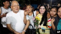 A prominent leader of Cambodia's land rights activist Tep Vanny, third from right, holds flowers as she celebrates upon the arrival at her home in Boeung Kak, in Phnom Penh, Cambodia, Aug. 20, 2018.