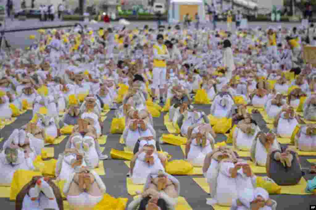 Participants dressed in white perform yoga at an event to celebrate the International Yoga Day under the Eiffel Tower in Paris, France, Sunday, June 21, 2015. Thousands of yoga enthusiasts took part in mass yoga programs to mark the first International Yo