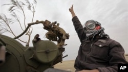 A Libyan rebel fighter manning an anti-aircraft gun flashes the victory sign as his vehicle advances towards the front line, on the outskirts of Ajdabiya, Libya, April 20, 2011