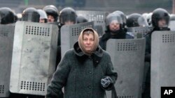 우크라이나 수도 키에프에서 21일에도 반정부 시위가 계속된 가운데, 한 여성이 진압 경찰 앞을 지나고 있다.