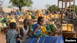 FILE - Children wait for their turn to buy water from a privately-owned water tower, amid an outbreak of the coronavirus disease, in Taabtenga district of Ouagadougou, Burkina Faso, April 3, 2020.