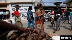 FILE - People walk past a snails vendor's stall at Adjame market in Abidjan, Ivory Coast September 15, 2022. 