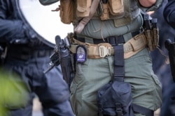 The badge on an Arlington County Police officer is seen as he aims a weapon as demonstrators are moved back after gathering to protest the death of George Floyd, June 1, 2020, near the White House in Washington.