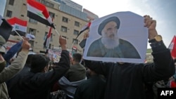 Para demonstran anti pemerintah membawa gambar Ayatollah Ali Sistani dalam aksi protes di lapangan Tahrir, Baghdad, Irak. 