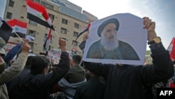 FILE - Iraqis carry pictures of the country's top Shi'ite cleric, Grand Ayatollah Ali al-Sistani, as they demonstrate in the capital Baghdad's Tahrir Square, Dec. 5, 2019. 