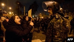 A woman attending a candlelight vigil in memory of the victims of a Ukrainian airliner downed by Iran talks to a policeman following the gathering in front of the Amirkabir University in Tehran, Iran, Jan. 11, 2020. 