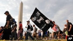 Juggalos, as supporters of the rap group Insane Clown Posse are known, march past the Washington Monument as they head towards the Lincoln Memorial in Washington during a rally, Sept. 16, 2017. 