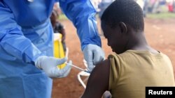 Un infirmier congolais administre le vaccin contre le virus Ebola à un garçon qui a été en contact avec une victime d'Ebola dans le village de Mangina, dans la province du Nord-Kivu, en RDC, le 18 août 2018.