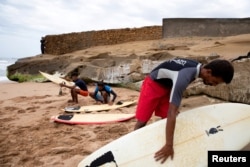 FILE - Surfers check their boards as they prepare to surf at Tushan Beach in Karachi, Pakistan, Aug. 28, 2024.