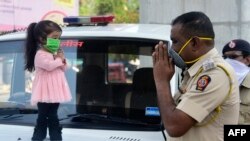 Guinness world record holder of the world's smallest living woman, Jyoti Amge (L), greets a police officer as she appeals citizens to stay inside their homes during a government-imposed nationwide lockdown as a preventive measure against the COVID-19 coro