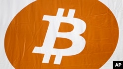 FILE - A bitcoin logo is displayed at the Inside Bitcoins conference and trade show in New York.