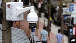 FILE - A surveillance camera is attached to a light pole along Boylston Street in Boston, April 14, 2014.