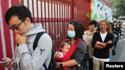 Warga Hong Kong antre di tempat pemungutan suara untuk memasukkan suara dalam pemilu lokal di Hong Kong, China, 24 November 2019. (Foto: Reuters)